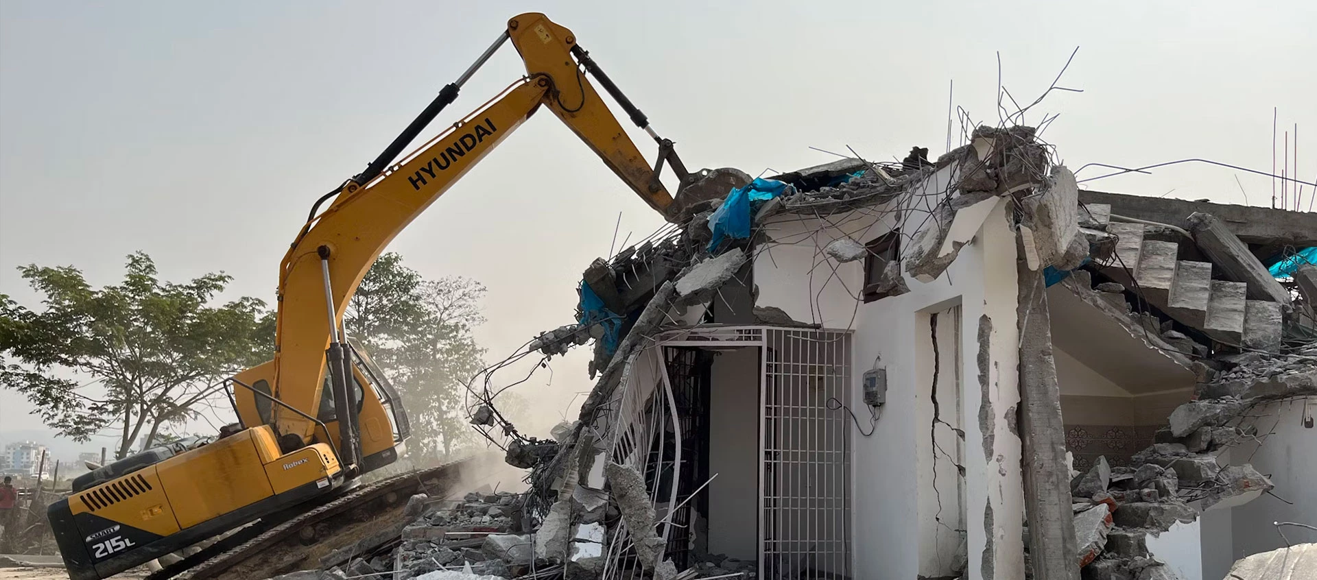 Ein gelber Bagger reißt ein Gebäude ab.
